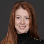 A person with long red hair and a black top smiles confidently, representing medbridge's healthcare education.