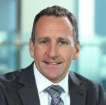 A professional man in a suit smiles, representing medbridge's impact on healthcare training and patient care innovation.