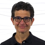 A person with short curly hair and glasses in a black shirt represents hybrid care by medbridge.