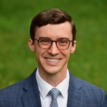 A smiling man with glasses in a blue suit represents Medbridge's commitment to digital healthcare education.