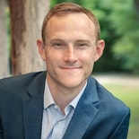 A person in a blue suit poses with greenery in the background, symbolizing medbridge's vision for healthcare education.