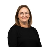 A woman with glasses and light brown hair smiles at the camera, representing medbridge healthcare training.
