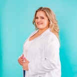 A woman in a white lab coat stands smiling against a turquoise background, representing medbridge.