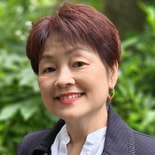 A woman with short dark hair and gold hoop earrings smiles outdoors, representing medbridge in digital healthcare.