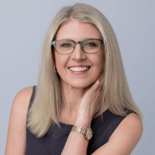 A woman with blonde hair and glasses smiles against a plain background, suitable for medbridge healthcare promotion.