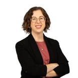 Smiling woman with short curly hair and glasses in business attire, representing digital health innovation at medbridge.