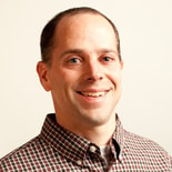 Man in a checkered shirt smiling, representing medbridge's blend of ease and professionalism in healthcare education.