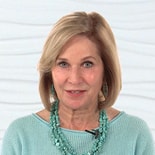 A woman with short blond hair wearing a turquoise necklace and sweater, set against a white textured background for medbridge.
