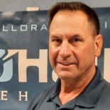 Man in a dark shirt stands before a banner with partial medbridge text visible.
