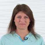 Smiling woman with long brown hair in blue top, representing welcoming patient care software by medbridge.