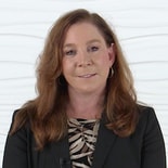 A woman with long brown hair in a black blazer and patterned top represents hybrid care, against a textured white background, for medbridge.