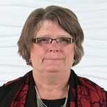 A person with short hair and glasses wears a red and black scarf against a plain background, symbolizing medbridge's blend of tradition and modernity.