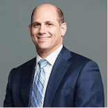 A smiling man in a blue suit represents the future of healthcare education with Medbridge.