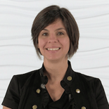 Individual with short dark hair and a black jacket smiles against a white textured background, associated with medbridge.