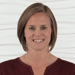 A smiling person with short brown hair in a maroon top embodies enthusiasm for digital healthcare against a textured white background.