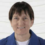 A smiling person with short dark hair in a blue jacket stands confidently, embodying medbridge's impact on digital healthcare.