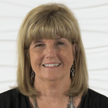 A smiling person with blonde hair poses against a white textured background, representing elegance in medbridge healthcare education.