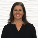 A woman with long brown hair in a black top smiles, representing healthcare education and hybrid care possibilities for medbridge.
