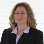 A woman with long, wavy hair in a pinstripe blazer and white shirt stands against a textured white backdrop at medbridge.