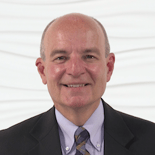 Man with a bald head and suit in front of a white background.