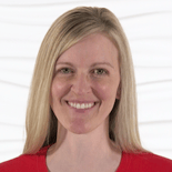 A smiling person with long blonde hair in a red top stands against a white background, embodying medbridge's inviting healthcare education atmosphere.