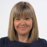 A smiling person with shoulder-length blonde hair, embodying the positive impact of medbridge healthcare education, is in front of a plain background.
