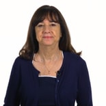 A woman with long dark hair in a navy blue top poses for a Medbridge photo.