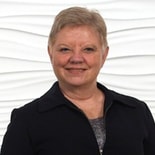 A woman with short blonde hair in a black jacket smiles, representing medbridge and digital healthcare's transformative impact.