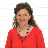 A person with curly hair and a beaded necklace smiles brightly, capturing the vibrant spirit of healthcare education for medbridge.