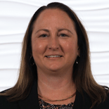 A smiling long-haired person in a dark blazer stands against a wavy white background symbolizing digital healthcare innovation.