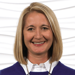 A smiling woman with blond hair, in a purple sweater over a white shirt, represents Medbridge's dedication to healthcare training.