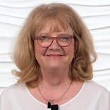 A smiling blonde woman in glasses and a white top represents healthcare education against a textured backdrop for medbridge.