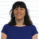 A woman in a blue top smiles against a white background, representing Medbridge's commitment to healthcare education.