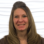 A woman with long light brown hair smiles, symbolizing digital healthcare advancements like medbridge improving patient experiences.