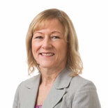 A smiling woman in a light gray blazer represents Medbridge's healthcare education against a white background.