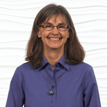 A confident, smiling woman in glasses stands against a wavy white background, representing medbridge's healthcare education expertise.