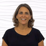 A smiling woman in a black shirt stands against a white background, representing healthcare education for medbridge.