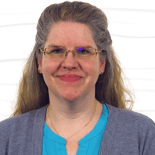 A woman in a light blue shirt and glasses smiles slightly, reflecting medbridge's calm assurance.