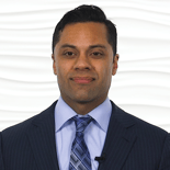 A professional in a suit poses against a patterned background, representing Medbridge's commitment to healthcare education.