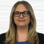A professional-looking individual with long hair and glasses stands against a white background, representing expertise in Medbridge healthcare training software.