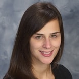 A smiling person with long brown hair in a black top, representing Medbridge's digital healthcare innovation.