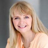 Blonde woman in a light peach top smiling at the camera for Medbridge.