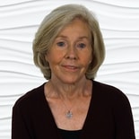 An older woman with short light hair, wearing a dark top and heart necklace, represents compassionate healthcare education against a wavy white background for medbridge.