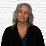 A woman with wavy hair wearing a black jacket stands against a white background, representing Medbridge hybrid care.
