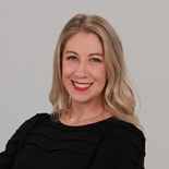 A smiling woman with long blonde hair in a black top represents enthusiasm for digital healthcare and Medbridge software.