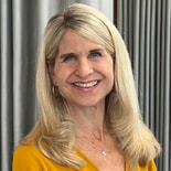 A woman in a yellow top stands smiling, representing healthcare education for medbridge.