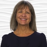Woman with shoulder-length hair in a dark top against a wavy white Medbridge background.