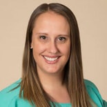 A smiling woman with long brown hair in a teal top represents Medbridge's digital healthcare spirit.
