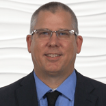 A smiling man in glasses and a suit represents the friendly professionalism of medbridge’s healthcare education.