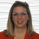 Smiling blonde-haired woman with glasses in a red top against a wavy white background, representing medbridge.